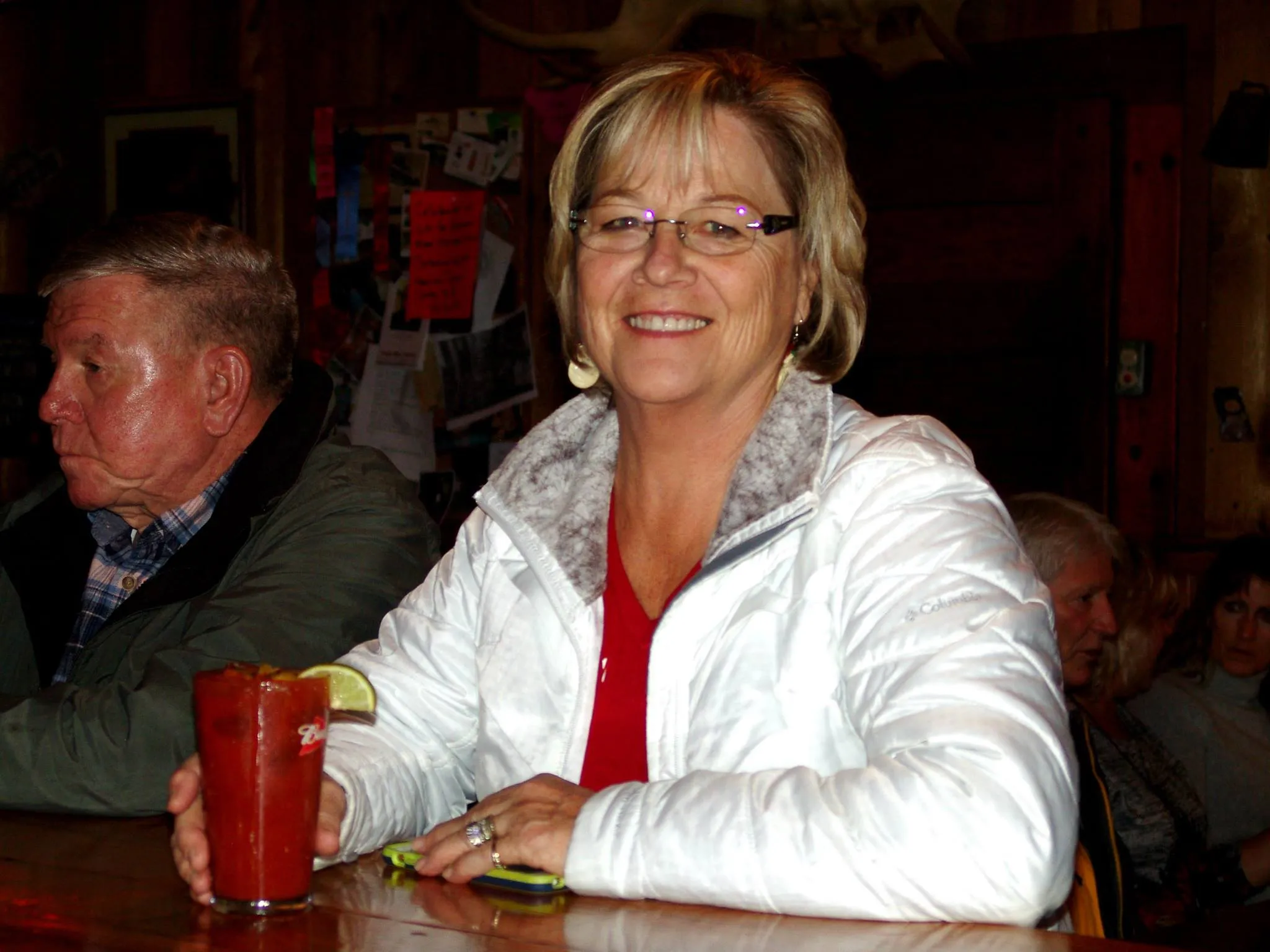 Regular at the bar with a Bloody Mary, smiling under the red neon glow.
