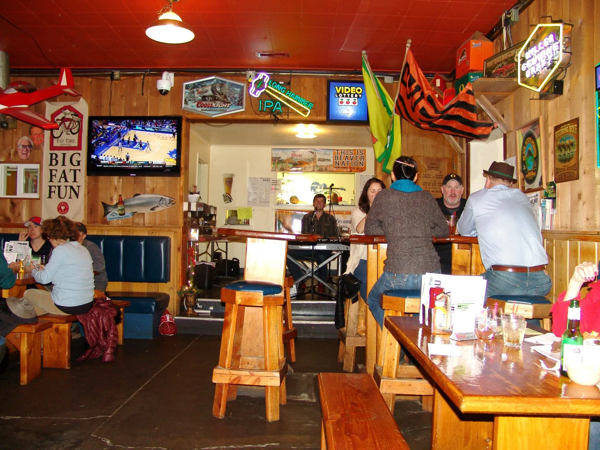 Wood-frame bar interior with neon beer signs on the walls, wooden tables and a crowd of diners.
